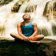 woman meditating under a flowing waterfall