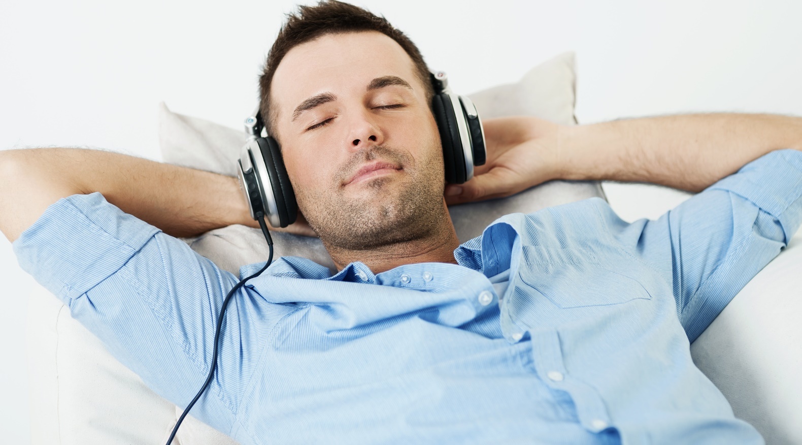 a relaxed man napping with headphones on