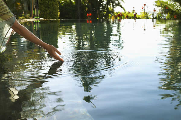 womans hand gently touching a lake