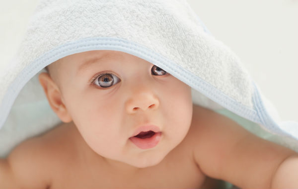 cute baby hiding under bed sheets