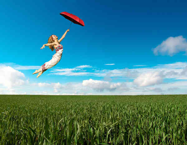 woman flying over the field by holding her umbrella