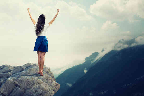 lady at mountain top with hands up