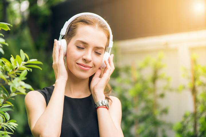 Woman relaxing while listening to a hypnosis session on headphones